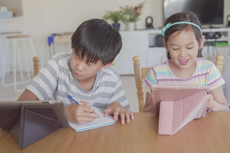 mixed Asian girl using digital tablet at home, listening to podcast, gaming, online education,...