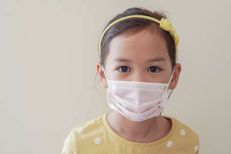 Asian little girl wearing medical face mask, self-quarantine,  coronavirus, covid-19  virus outbreak epidemic pandemic, pm 2.5 air pollution and health conceptの写真素材