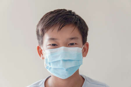 Asian preteen boy wearing medical face mask, self-quarantine,  coronavirus, covid-19  virus outbreak epidemic pandemic, pm 2.5 air pollution and health conceptの写真素材