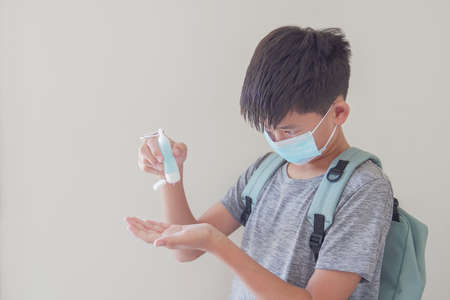 Mixed Asian preteen boy wearing mask and applying hand sanitizer, school reopen, back to school after covid-19 coronavirus pandemic is over, new normal conceptの写真素材