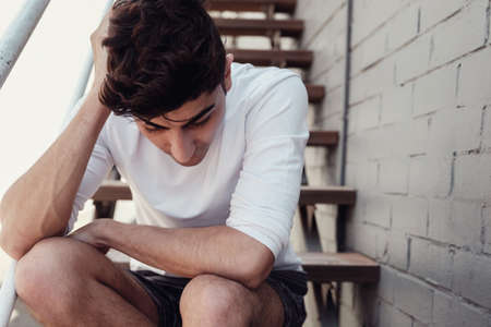 Depressed young adult man sitting alone, mental health conceptの写真素材
