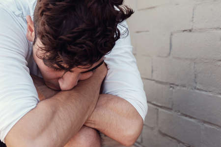 Depressed young adult man sitting alone, mental health conceptの写真素材