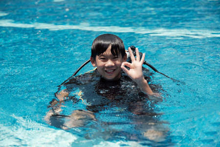 Young little Asian boy scuba diver showing ok hand signal, diving lessons for beginnersの写真素材
