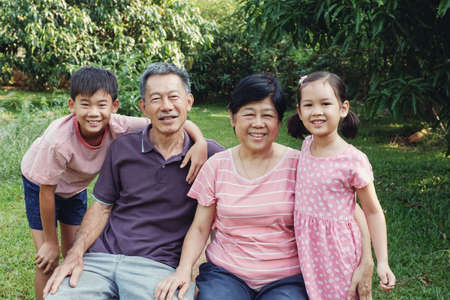 Asian grandchildren laughing with their grandparents in the park, Happy Asian familyの写真素材