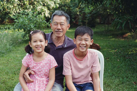 Asian grandchildren laughing with their grandfather in the park, Happy Asian senior manの写真素材