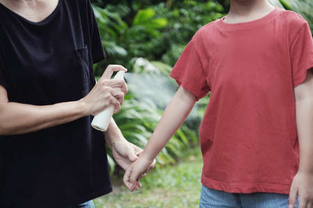 Parent spraying insect repellent on her son skin, using mosquito spray outdoorの写真素材