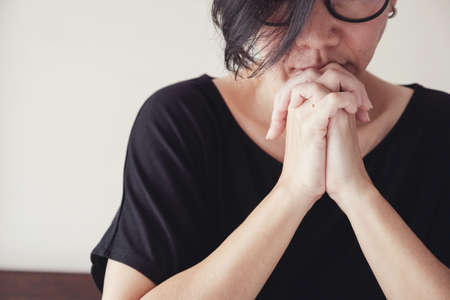 Asian middle aged woman wear glasses praying with hands together in the morningの写真素材