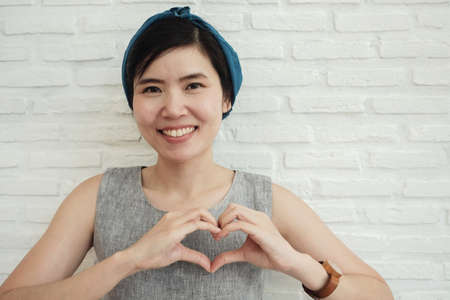 Happy Asian young woman making her hands in heart shape, heart health insurance, social...