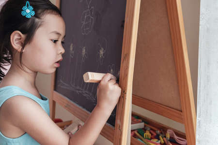 Young Asian girl drawing on chalkboard, montessori homeschool educationの写真素材