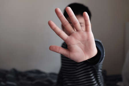 Young Asian preteen teenager boy showing a stop sign with his hand, Stop bullying children, stop domestic violence concept, mental health problemの写真素材