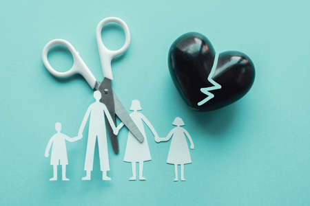 White scissor cutting family paper cut out holding black heart balloon on blue background, causes and effects on child development and behavior of dysfunctional family, divorce broken home concept, mental healthの写真素材