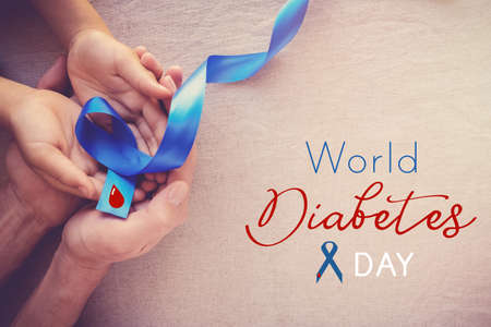 adult and child hands holding Blue ribbon, world diabetes dayの写真素材