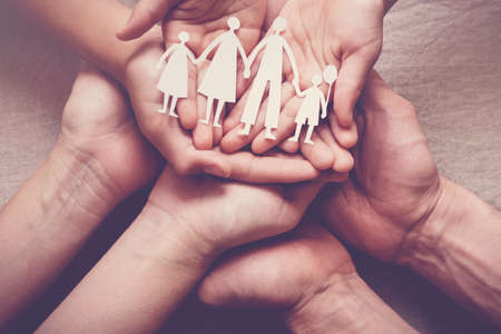 Adult and children hands holding paper family cutout, family home, foster care, homeless support conceptの写真素材