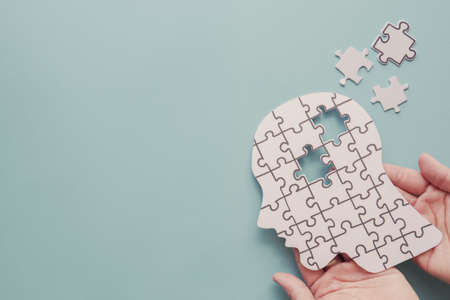 Hands holding brain with puzzle paper cutout, autism, memory loss, dementia and alzheimer awareness,...