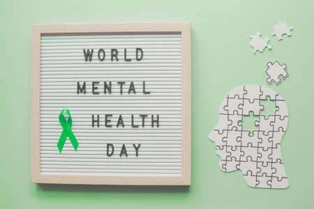 World mental health day and green ribbon on letter board with head and puzzle paper cutoutの写真素材