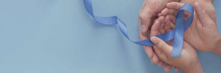 adult and child hands holding blue ribbon on blue background , Prostate Cancer Awareness, Movember Men health awareness, November Blue, world diabetes dayの写真素材