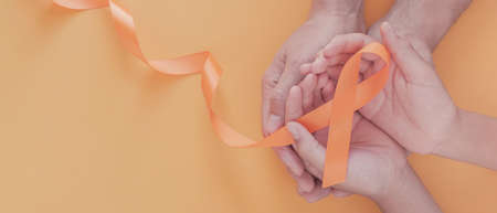 Adult and child hands holding orange Ribbons,  Leukemia cancer and Multiple sclerosis, COPD and ADHD awareness, world kidney dayの写真素材