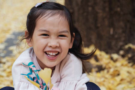 Happy little Asian girl  smiling with yellow ginkgo leaves background in Tokyo Japan Autumn