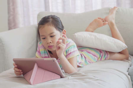 mixed Asian girl using digital tablet at home, learning maths, listening to podcast, gaming, online education, elearning, homeschooling, social distancing, isolation, lockdown conceptの写真素材