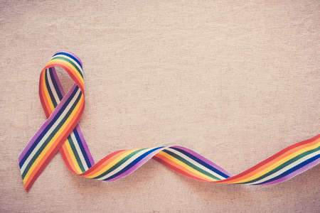Hands holding gay pride rainbow ribbon for LGBT awarenessの写真素材