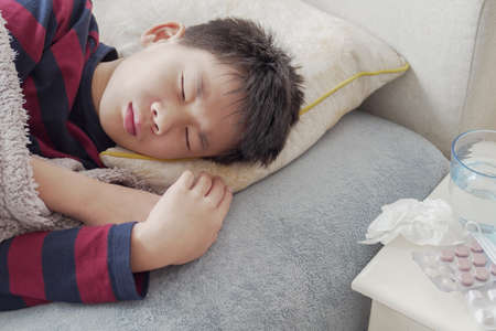 Sick preteen boy resting on sofa with medication
at home, heath care conceptの写真素材