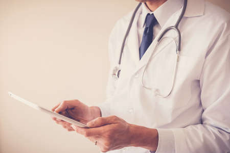 Medical doctor hands holding tablet, using app working remotely, telehealth, online health technology conceptの写真素材