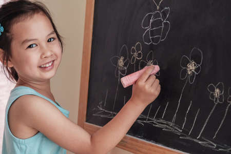 Young Asian girl drawing on chalkboard, montessori homeschool educationの写真素材