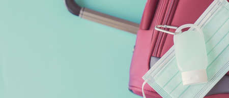 Hand sanitizer, face mask on red suitcase, reopen tourism, new normal for traveling conceptの写真素材
