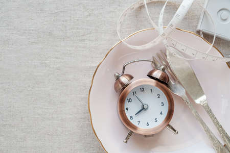 A clock on the plate and tape measure, Intermittent fasting diet conceptの写真素材