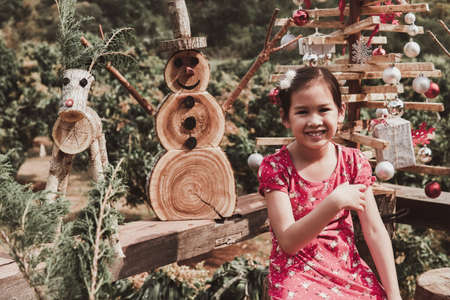 Happy little mixed race young girl with Christmas festive decoration made from reusable wood, sustainable lifestyleの写真素材