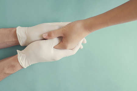 Hands with gloves holding child hand, helping hands, compassion, donation, volunteer and charity conceptの写真素材