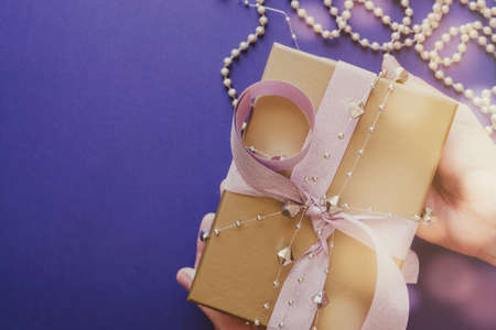 Hands holding Golden gift box with glitter pink ribbon, festive holidays christmas new year 2021 backgroundの写真素材