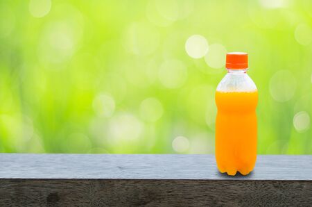 orange juice bottle on wood table with fresh green background. natural healthy drink.の写真素材