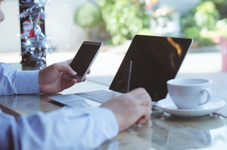 casual business man or freelance woring on computer laptop and typing on keyboard with cofee cup on the desk in coffee shop.の写真素材