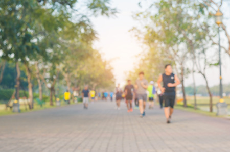 blur group of people exercise with running or jogging on the morning with sun light in the park for...