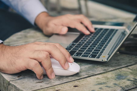 attractive hand of business man using laptop working typing on key board with coffee cup in coffee...