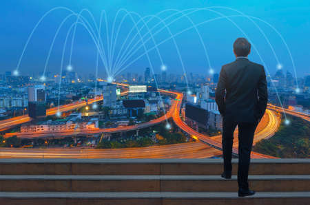 Businessman looking over night cityの写真素材