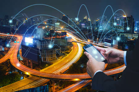 Businessman using touching button on mobile phone and link money point to cityの写真素材