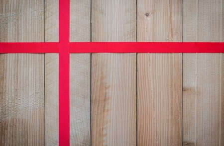 red silk ribbon lay cross on wooden table background with copy space for text design decoration  for other holiday festive.の写真素材