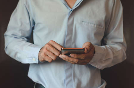 businessman using mobile phone touch screen in office with hands typing smart phone texting messaging lifestyle working app device technology internet social data online concept vintage style.の写真素材