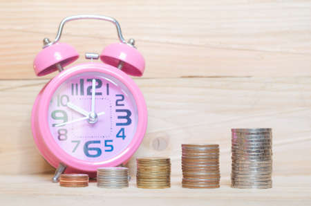 business and financial concept idea golden coin stacking and antique clock on wood background for saving coin growth up wealth successful for investment in future or save money for retirement.の写真素材