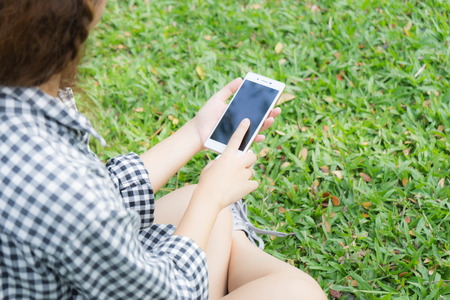 girl sitting in garden and use smart phoneの写真素材