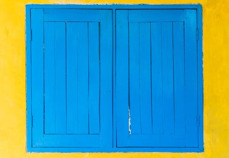 blue window on yellow wallの写真素材