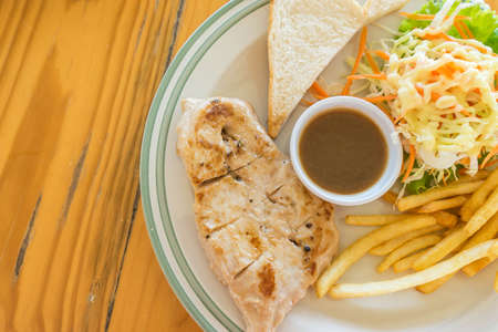 chicken steak serve with french fried salad and breadの写真素材