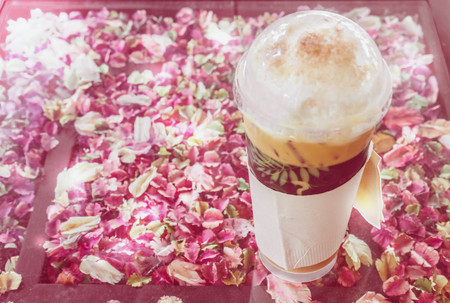 plastic cup of ice cappuccino on glass table that contain a lot of dry petal,blur sweet pictureの写真素材