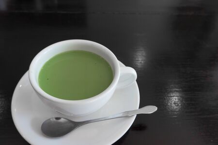 hot milk green tea in white teacup , black wooden backgroundの写真素材