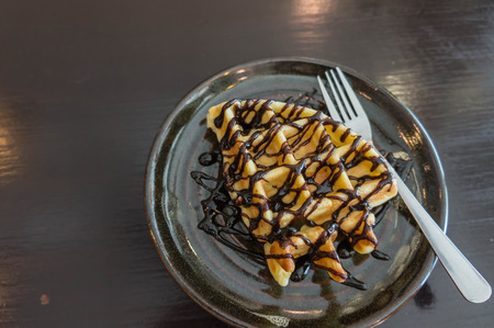 waffle ,choccolate topping on black plate , wooden black backgroundの写真素材