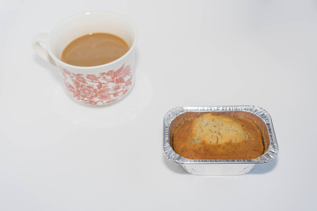 banana cake in aluminum foil and a cup of hot milk tea on white backgroundの写真素材