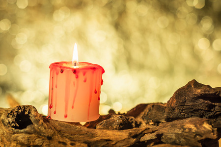close-up of horror candle on wooden timber in warm light, beautiful bokeh background, soft focusの写真素材