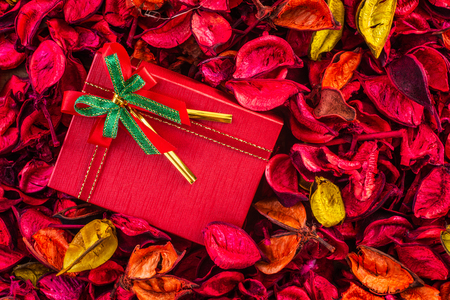 Red gift box tied with red ribbon and bow on dry flower, top view, vintage toneの写真素材